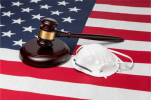 A mask and gavel sitting on an American flag. 